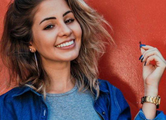 Woman in blue shirt with blue nails smiling