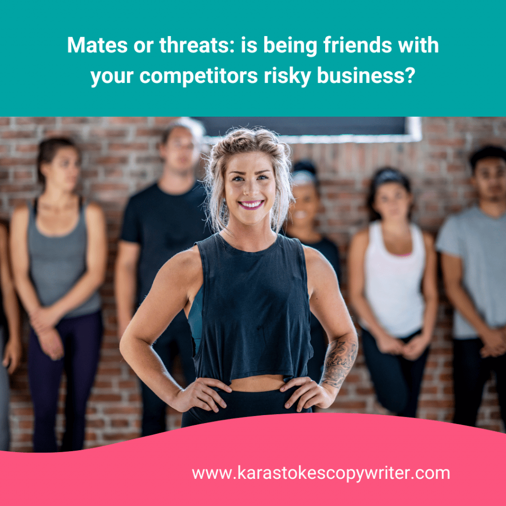 A woman with curlay hair pulled back in a loose bun wears a crop top and stand with her hands on her hips. Behind her is a group of people in fitness gear, lined up and leaning against a brick wall.