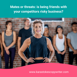 A woman with curlay hair pulled back in a loose bun wears a crop top and stand with her hands on her hips. Behind her is a group of people in fitness gear, lined up and leaning against a brick wall.