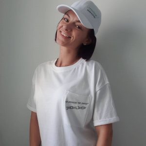 Jess-Lea-Lifestyle-Overhaul Jessica Lea smiling in a white cap and t-shirt with Lifestyle Overhaul logo on the chest