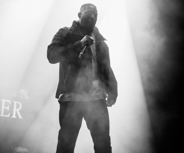 Man in a cap and leather jacket surrounded by smoke on a stage, black and white image
